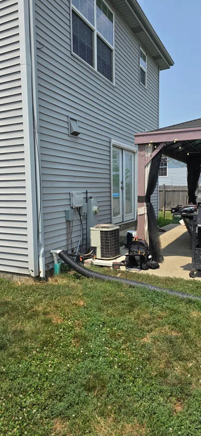 New AC condenser installed beside a two-story home by Heavy Duty Heating and Cooling