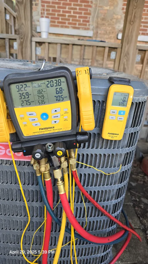 HVAC technician checking AC refrigerant pressures with manifold gauges